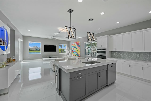 kitchen featuring sink, appliances with stainless steel finishes, a kitchen island with sink, hanging light fixtures, and white cabinets