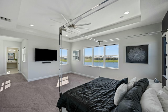 carpeted bedroom with ceiling fan, a tray ceiling, and multiple windows