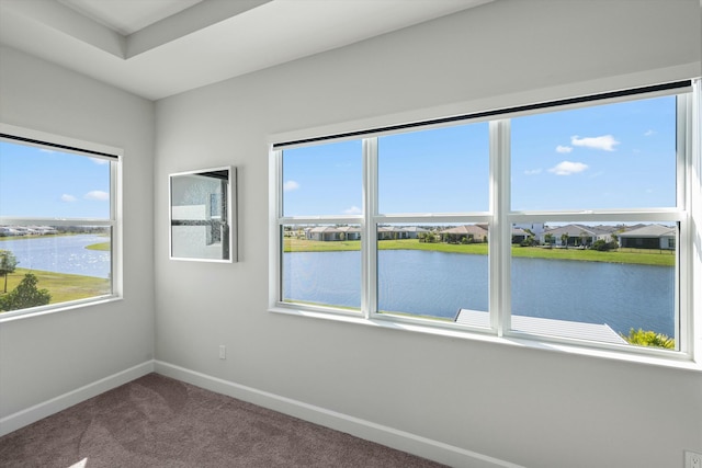 spare room with a water view and carpet floors