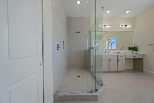 bathroom featuring tiled shower, vanity, and tile patterned flooring