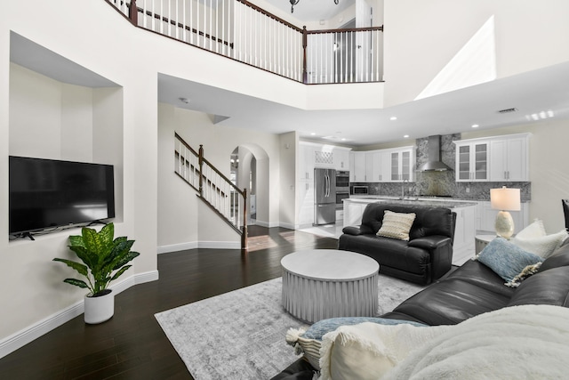 living room with dark hardwood / wood-style flooring, a towering ceiling, and sink