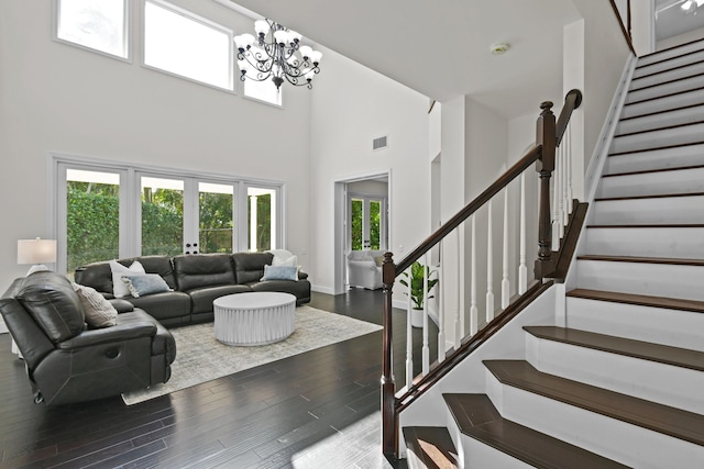 living room featuring a wealth of natural light, dark hardwood / wood-style floors, a high ceiling, and an inviting chandelier