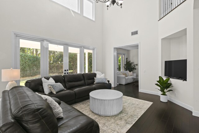 living room with dark hardwood / wood-style flooring, a chandelier, and a high ceiling