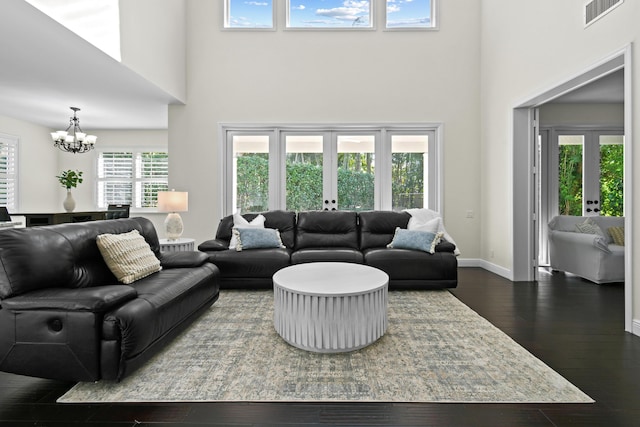 living room with french doors, a towering ceiling, and hardwood / wood-style floors