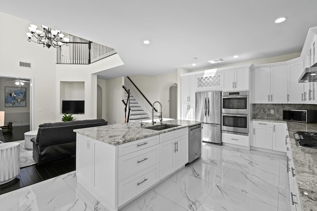 kitchen with light stone counters, sink, a kitchen island with sink, and appliances with stainless steel finishes