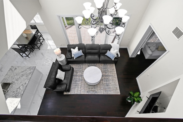 living room with hardwood / wood-style floors, a chandelier, and a high ceiling