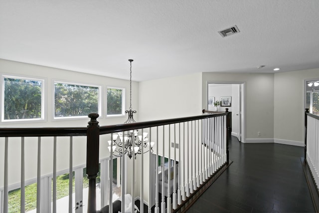 corridor featuring dark hardwood / wood-style flooring, a chandelier, and a textured ceiling