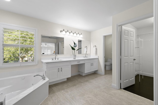 bathroom featuring a tub to relax in, ceiling fan, vanity, and toilet