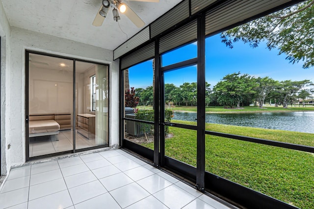 unfurnished sunroom with ceiling fan and a water view