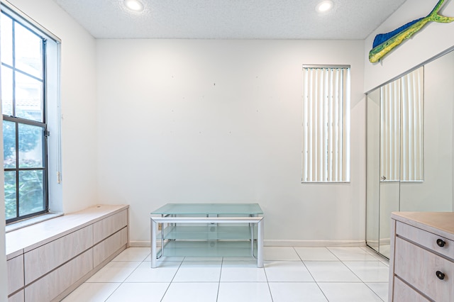 bathroom featuring tile patterned flooring, a textured ceiling, and a healthy amount of sunlight