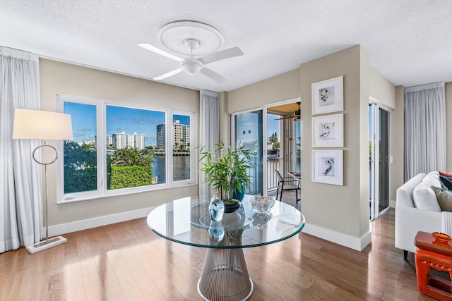 dining room featuring hardwood / wood-style floors, ceiling fan, and a textured ceiling