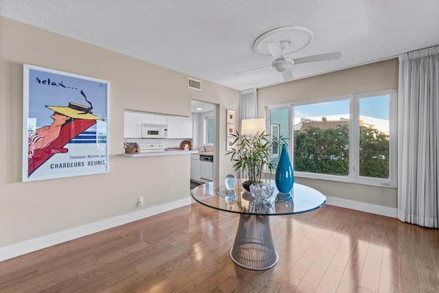 dining room featuring ceiling fan, light hardwood / wood-style floors, sink, and a textured ceiling