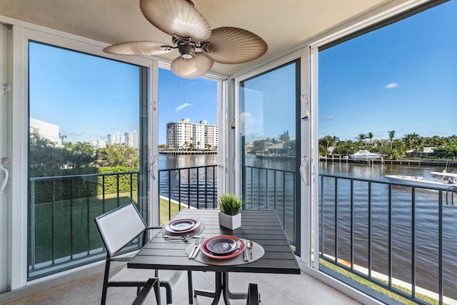 sunroom / solarium with a wealth of natural light, a water view, and ceiling fan