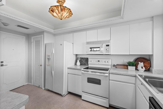 kitchen featuring white cabinetry, sink, pendant lighting, white appliances, and a tray ceiling