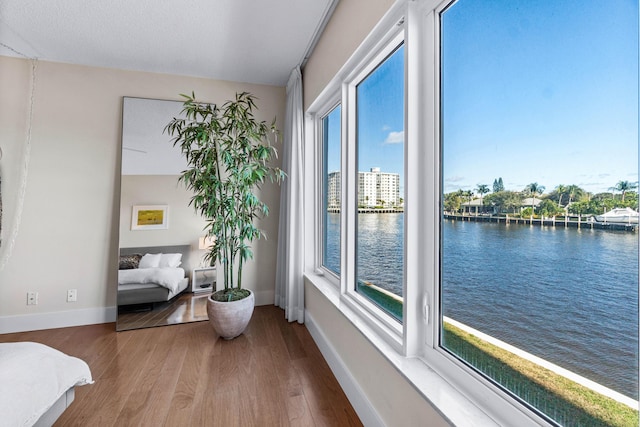 bedroom with hardwood / wood-style floors and a water view