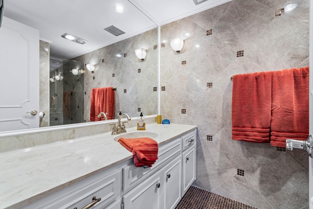 bathroom with vanity, tile walls, and a shower with shower door