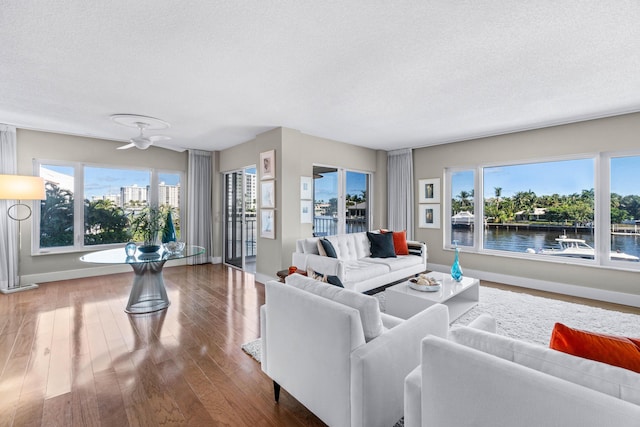 living room with plenty of natural light, a water view, and a textured ceiling