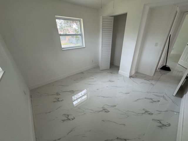 unfurnished bedroom featuring marble finish floor and baseboards