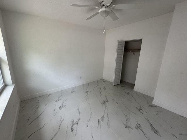 unfurnished bedroom with marble finish floor, a closet, a ceiling fan, and baseboards