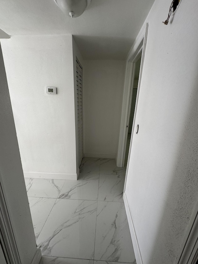 corridor with marble finish floor and baseboards