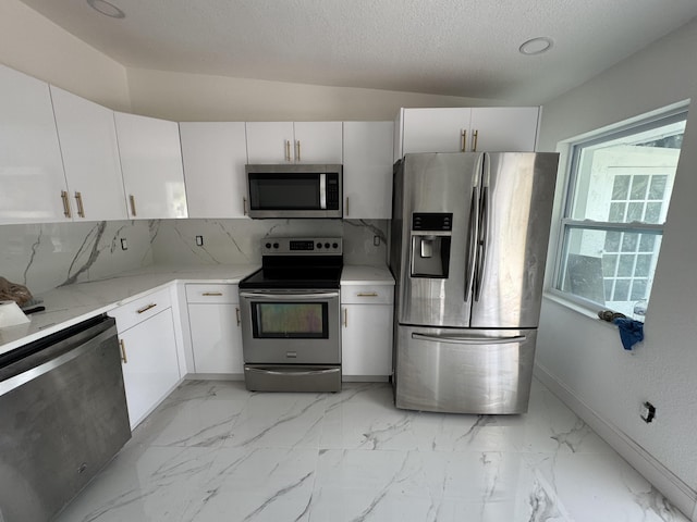 kitchen with decorative backsplash, appliances with stainless steel finishes, marble finish floor, a textured ceiling, and white cabinetry