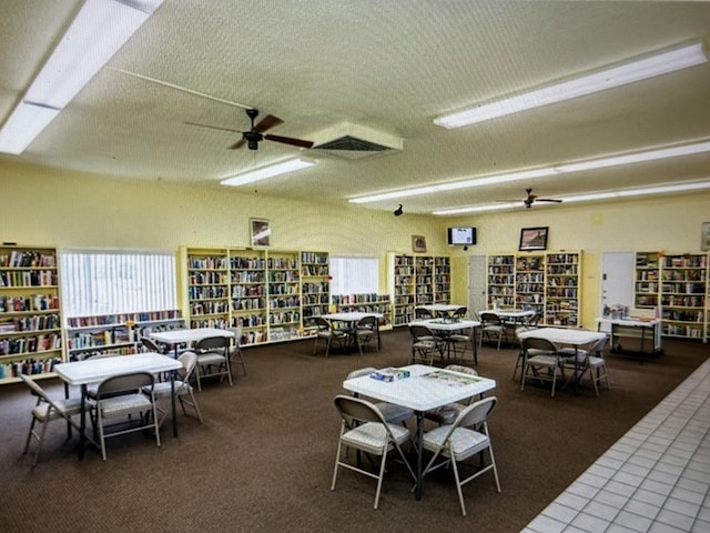 carpeted dining room with ceiling fan and a textured ceiling