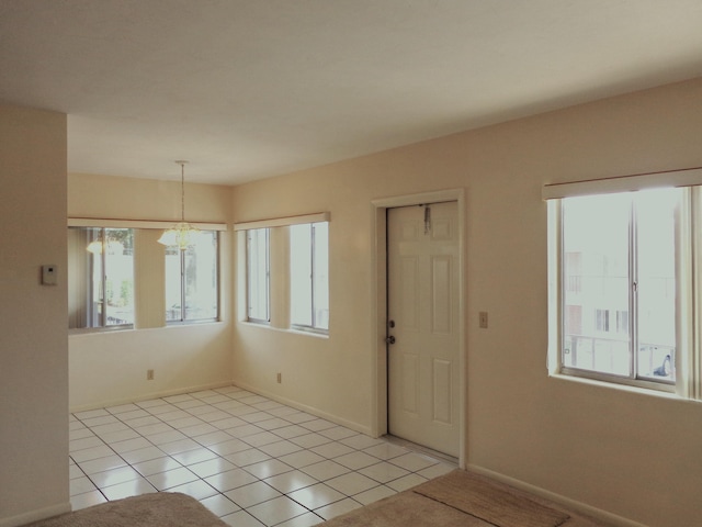 tiled empty room featuring a chandelier