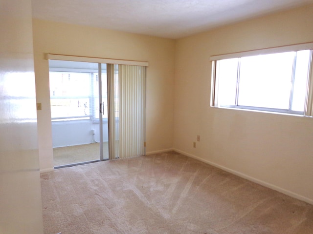 unfurnished room featuring a wealth of natural light and light carpet