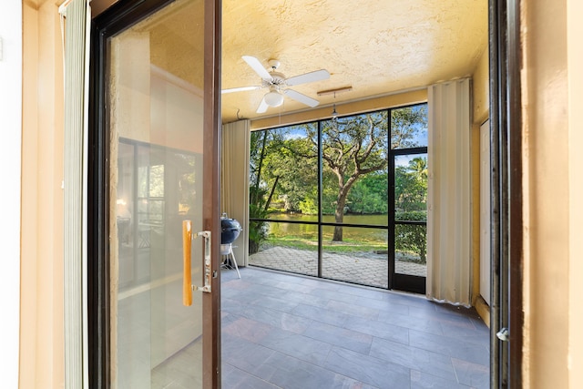 unfurnished sunroom featuring ceiling fan