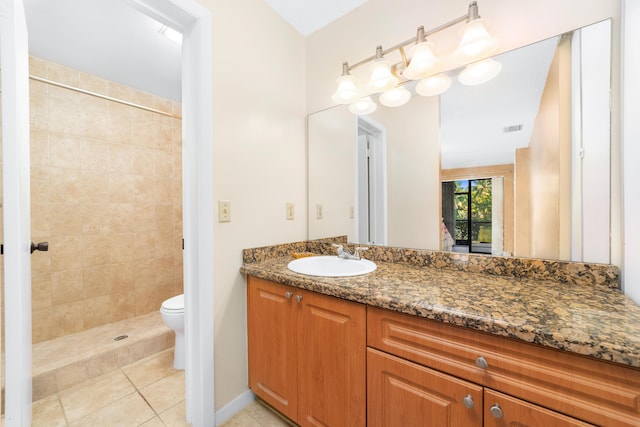 bathroom with tile patterned flooring, vanity, toilet, and tiled shower