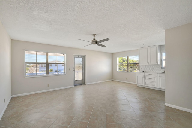 unfurnished living room featuring ceiling fan, light tile patterned floors, and a textured ceiling