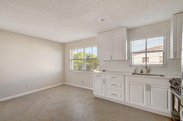 kitchen with tasteful backsplash, white cabinets, sink, and stainless steel range with electric cooktop