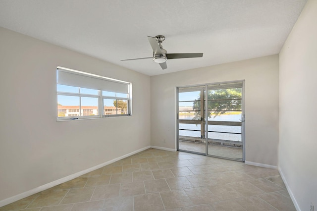 empty room featuring light tile patterned floors, a wealth of natural light, and ceiling fan