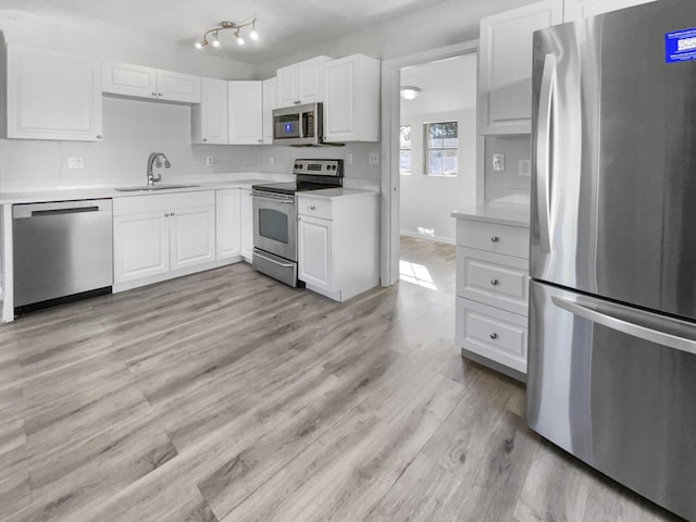 kitchen with white cabinets, light wood-type flooring, stainless steel appliances, and sink