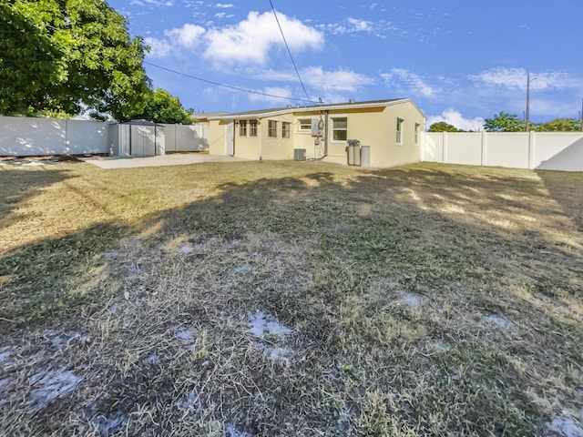 back of house featuring a lawn, central air condition unit, and a storage shed