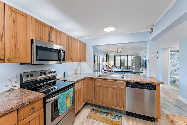 kitchen with kitchen peninsula, sink, stainless steel appliances, and light hardwood / wood-style floors