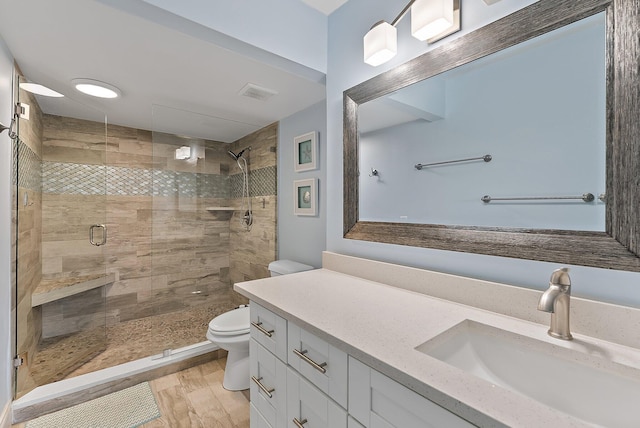 bathroom with hardwood / wood-style floors, vanity, toilet, and walk in shower