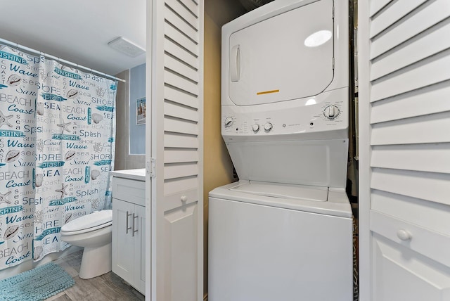 clothes washing area featuring stacked washing maching and dryer and light hardwood / wood-style flooring