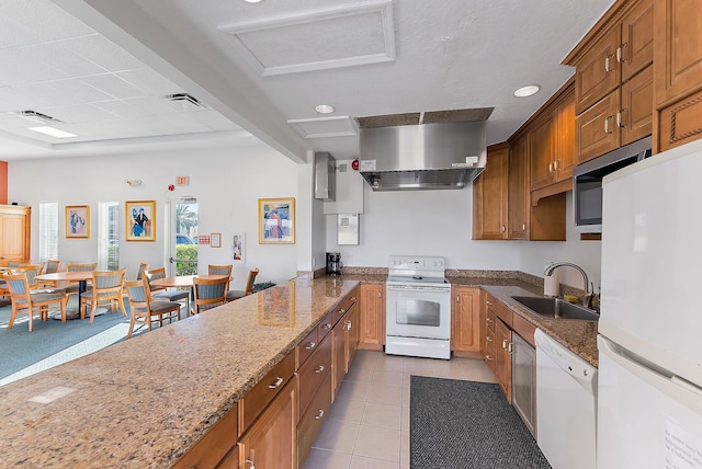 7370 S Ocean Dr Unit 111, Jensen Beach, FL 34957 - kitchen featuring white appliances, tile patterned flooring, exhaust hood, brown cabinetry, and stone countertops