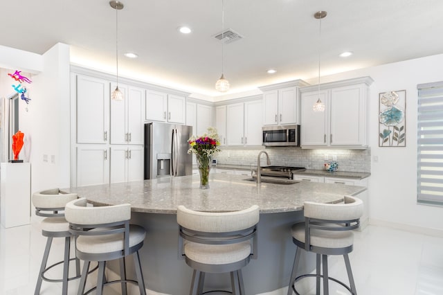 kitchen with appliances with stainless steel finishes, a breakfast bar area, sink, and hanging light fixtures