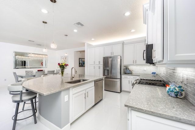 kitchen featuring appliances with stainless steel finishes, pendant lighting, white cabinetry, an island with sink, and sink