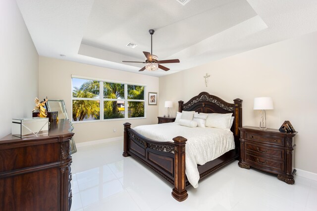 bedroom with a raised ceiling, light tile patterned floors, and ceiling fan