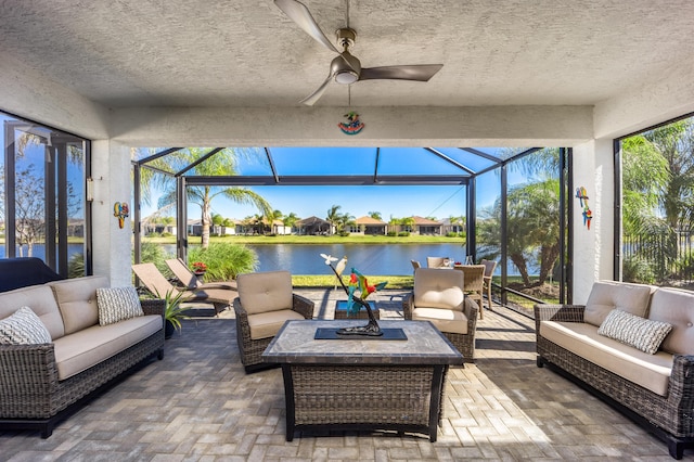 sunroom featuring ceiling fan and a water view