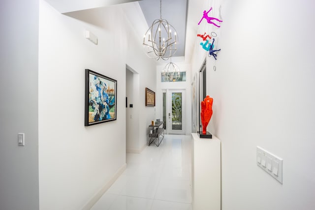 hallway with a notable chandelier and light tile patterned floors