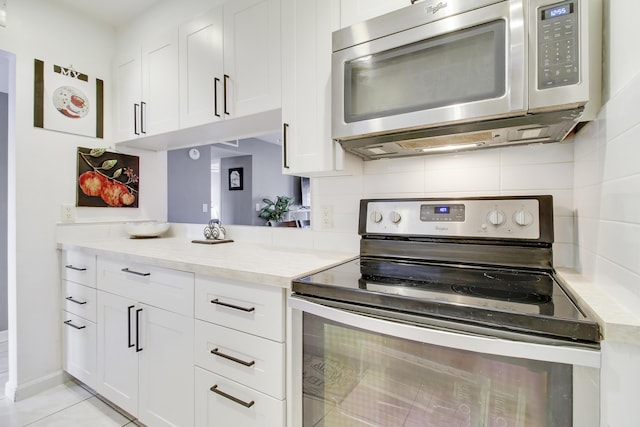kitchen with white cabinets, light stone countertops, backsplash, and appliances with stainless steel finishes