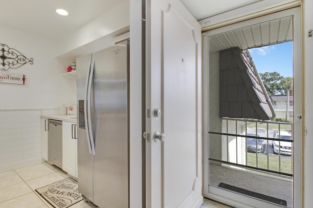 kitchen with white cabinets, appliances with stainless steel finishes, a healthy amount of sunlight, and light tile patterned flooring