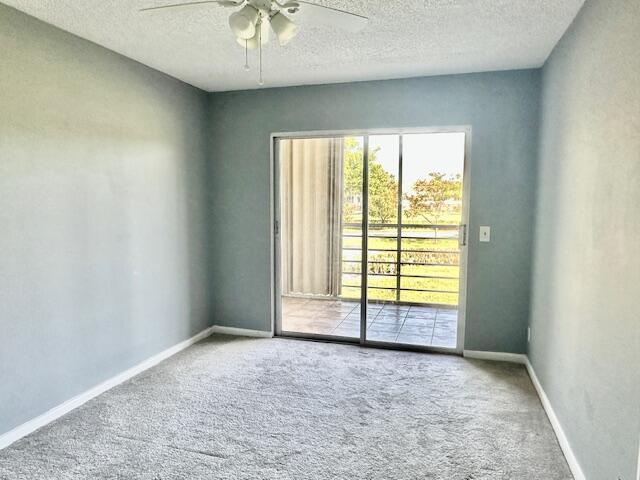 carpeted empty room with ceiling fan and a textured ceiling