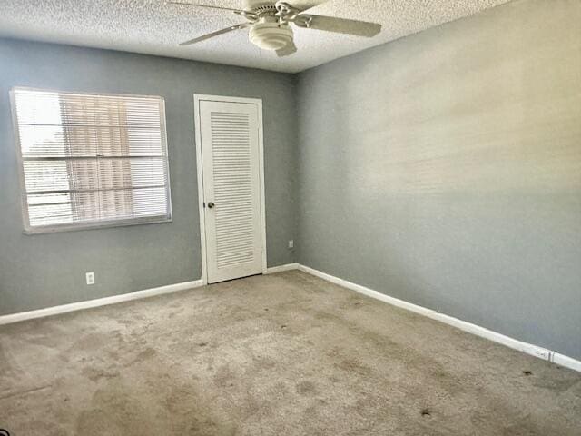 carpeted empty room featuring ceiling fan and a textured ceiling