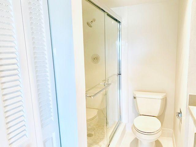 bathroom featuring tile patterned flooring, vanity, toilet, and an enclosed shower