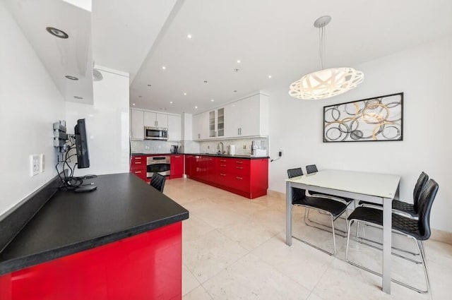 kitchen with backsplash, stainless steel appliances, sink, decorative light fixtures, and white cabinets